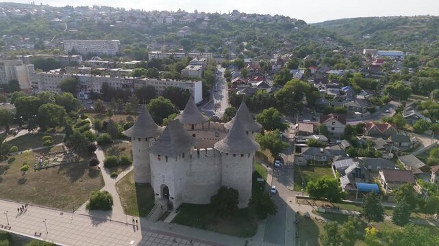 Cinematic aerial view of the medieval Soroca Fortress in Moldova. Drone shot of the circular stone castle on the banks of the Dniester River with park and cityscape in the background.