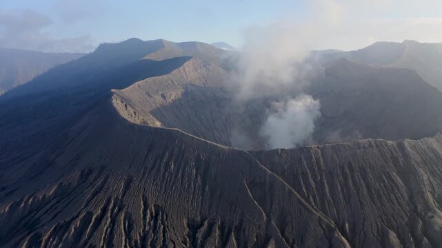 Aerial view of Mount Bromo crater with rising smoke and rugged volcanic slopes in Tosari, East Java, Indonesia.