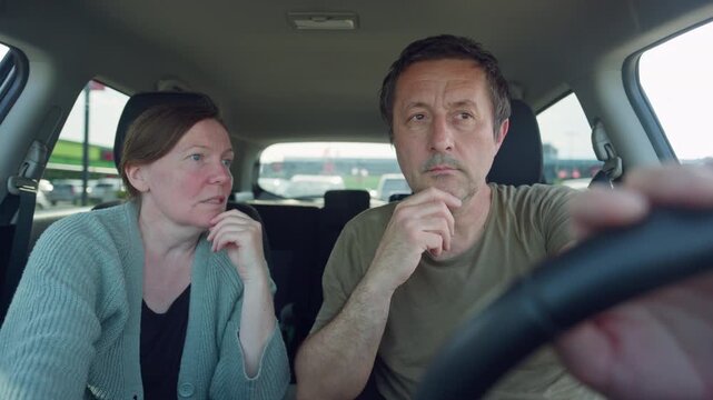 Couple sitting in car looking thoughtful and talking while driver considers route during road trip, 4K