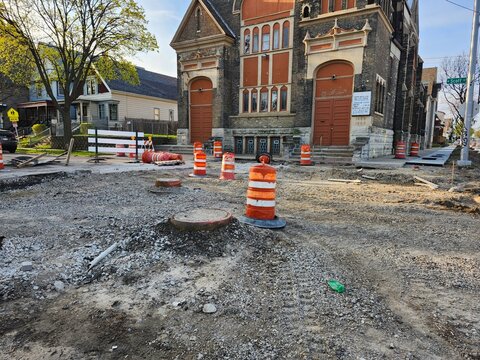 Road construction site with traffic cones and exposed manhole in urban neighborhood