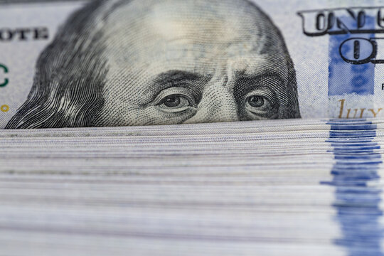 Macro extreme close up of Benjamin Franklin eyes on hundred dollar bill stack