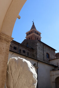 Scorcio prospettico del campanile romanico della Chiesa di Santa Maria Maggiore a Tivoli incorniciato da un arco del chiostro con frammenti marmorei