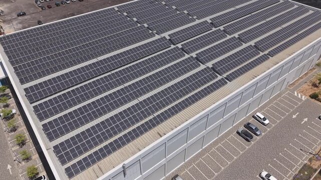 Aerial view of a large commercial building with full rooftop solar panel installation and parking lot in an Israeli industrial area
