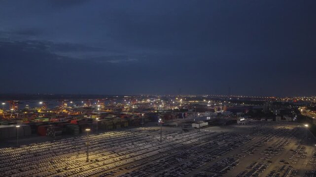 Night aerial view of vast port logistics area with car yard and industrial lights