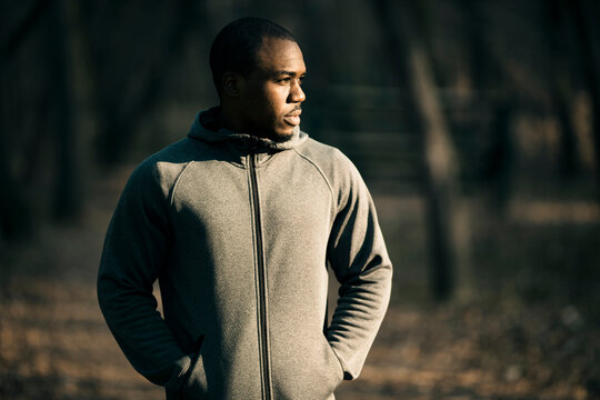 Man in gray hoodie standing on forest trail