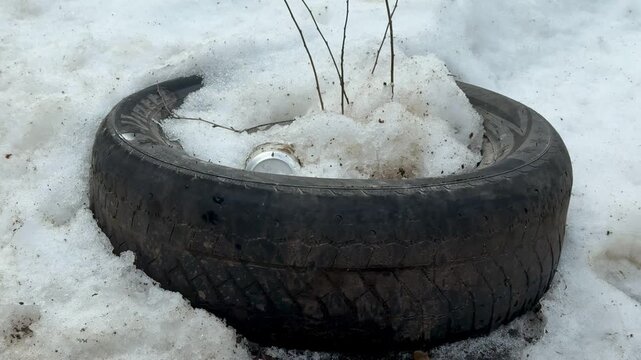 Old Tire In Melting Snow Field, Abandoned On Dirty Roadside With Slushy Ice And Scattered Debris Cold Bleak Atmosphere Evokes Urban Neglect