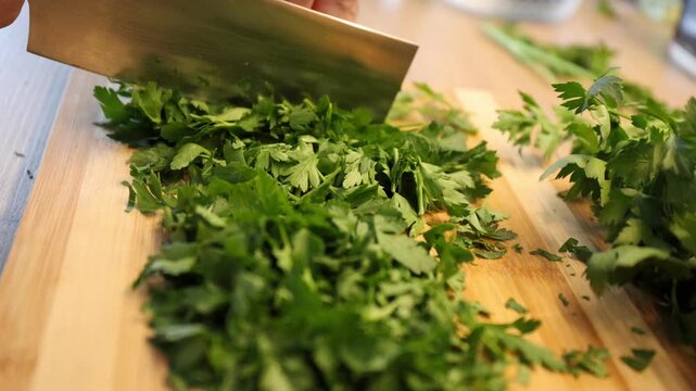 Slicing, cutting green parsley on a cutting board with a knife for cooking vegetarian food cook hands.