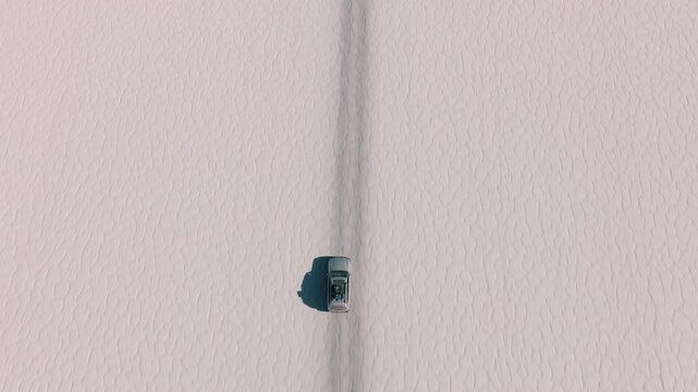 4x4 vehicle driving across the Uyuni salt desert in Bolivia, crossing vast white plains under a clear sky. Minimalist landscape with endless horizon and remote travel adventure.