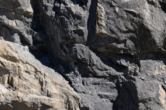 dettagli di una parete rocciosa naturale dalle tonalit&agrave; di grigio, illuminata dal sole