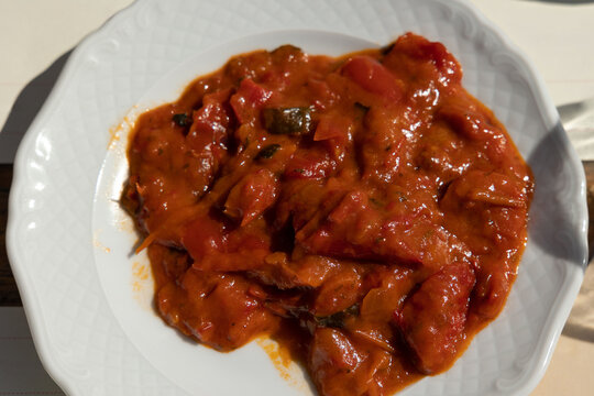 peperonata su piatto bianco, pietanza a base di peperoni tagliati a fette e stufati in padella con aglio, cipolla e salsa di pomodoro
