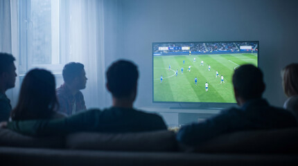 Group of friends watching soccer match on television in living room with soft lighting. Concept of global sports celebration, international football competition © Nataschen