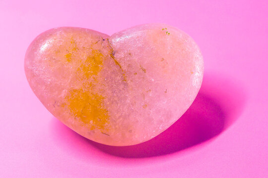 heart-shaped quartzite rock with pink background and shadow