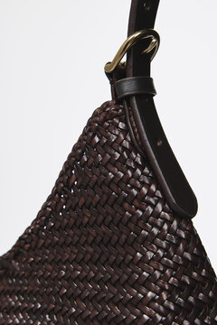 A close-up of a fashion bag against a white background. The texture of the leather and fabric