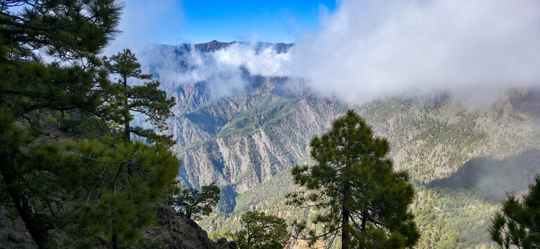 View of the peaks of the volcanic mountain range of the Caldera de Taburiente peeking out from behind the clouds from the side of Mount Pico Bejenado