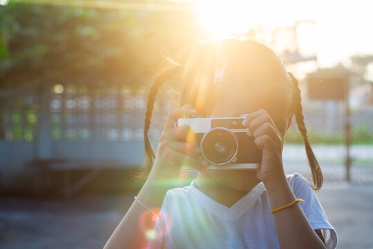 Little Girl Taking Photo with Vintage Film Camera at Golden Hour