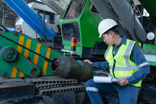 Engineer checks crane hook block and wire rope during inspection, supporting safety, maintenance, lifting readiness, and heavy equipment reliability in a crane yard.