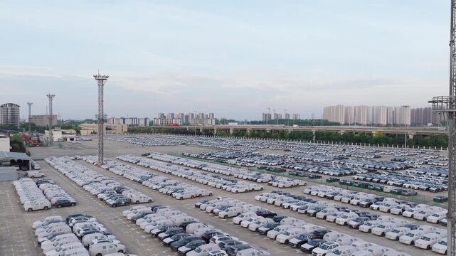 Large vehicle storage yard at seaport with control tower and rows of white cars