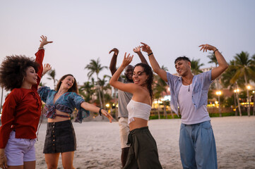 Obraz premium Energetic friends celebrating a summer party on the beach at sunset, embodying the carefree vacation