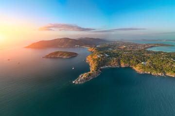 Obraz premium An expansive aerial view reveals the stunning Phuket coastline nai harn beach Promthep Cape, with a wide sandy beach curving into a bay dotted with numerous boats
