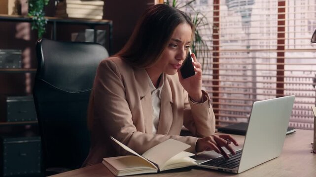 Emotional Caucasian business woman busy work many tasks talking phone typing laptop chat looking in notes girl executive office businesswoman working computer searching information multitask stress
