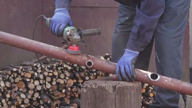 An industrial worker uses a powerful electric angle grinder to polish and cut a metal pipe, ensuring maximum precision and safety for professional metal fabrication site construction
