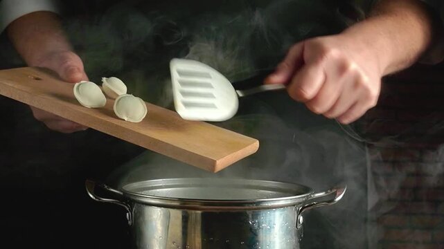 Chef adds dumplings with a spatula from a wooden board, placing them over a steaming pan in a cozy kitchen, demonstrating the cooking process with visible steam and kitchen elements