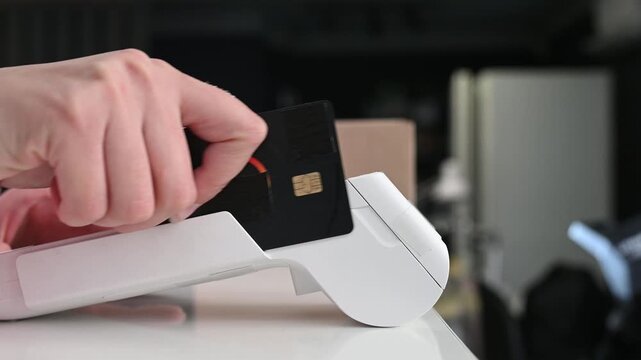 Paying with a magnetic stripe card for parcel delivery. Electronic cashless payments. Online shopping. A woman enters a PIN code on a wireless payment terminal.