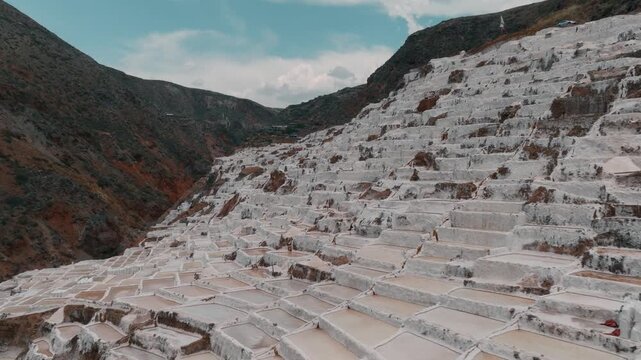 Drone aerial view of the historic Maras Salt Mines near Cusco, Peru. Thousands of terraced salt evaporation ponds cover the mountainside, creating a striking geometric pattern in the heart of the Sacr