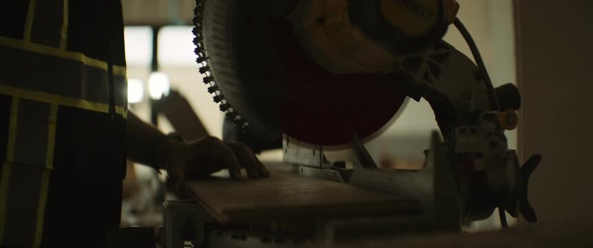 Close-up of a contractor using a power tool during interior construction or home renovation work with cinematic warm lighting and shallow depth of field.