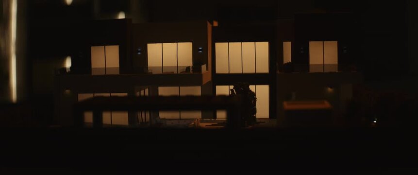 Cinematic close-up of an illuminated miniature architectural model showcasing modern residential design, interior lighting, and contemporary real estate development.