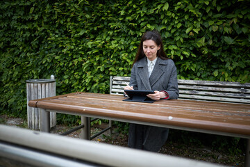 Fototapeta premium Woman working on a tablet computer outdoors on a wooden picnic table