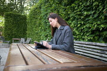 Fototapeta premium Woman using a tablet and stylus while sitting at an outdoor cafe table
