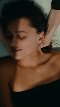 Holistic practitioner ear and neck acupressure on relaxed woman