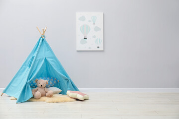 Wigwam, toy bear, pillows and picture in child's room, space for text © New Africa