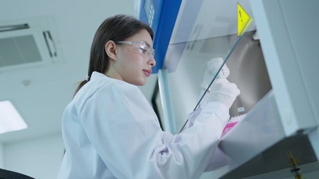 A scientist looks through a microscope to analyze samples in a laboratory. The walls are bright and the equipment is new. The focus is on research and findings.