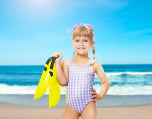 Cute little girl in swimsuit with flippers and goggles on beach © New Africa