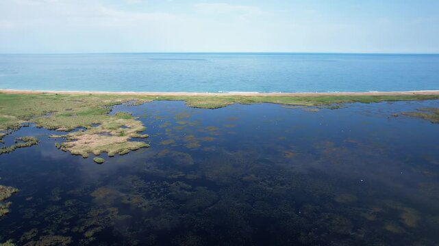 Aerial view of Durankulak Lake and the Black Sea coast with a narrow sandbar and green reeds in Durankulak, Dobrich Province, Bulgaria.