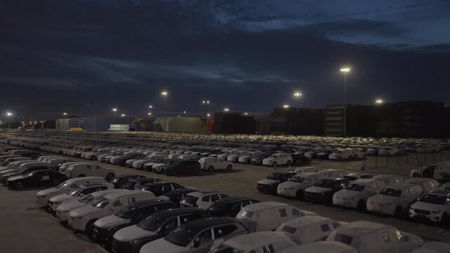 Night view of rows of export cars in port logistics yard under dark sky