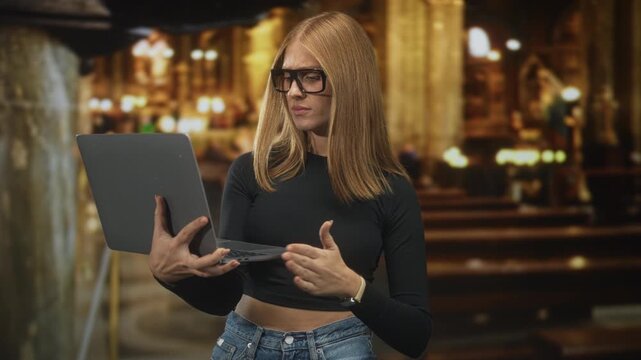 Redhead woman holding laptop with one hand and gesturing with the other in a church setting; contemplation study.
