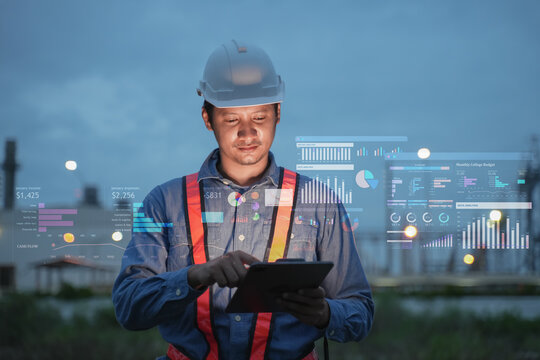 Industrial engineer using tablet with digital analytics dashboard at construction site at dusk
