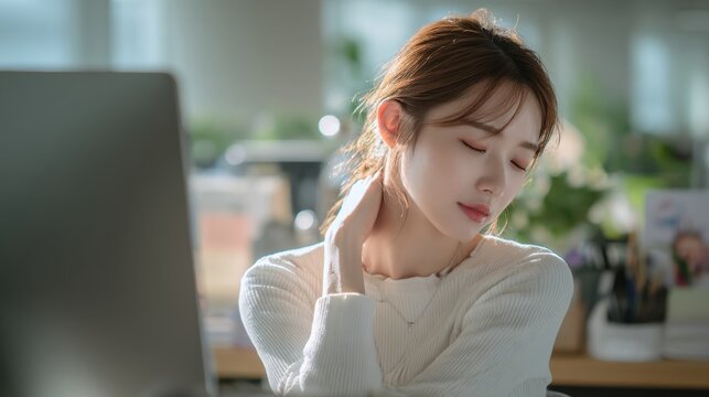 Female diversity. Human rights, equal opportunity concept. A portrait of a young woman seated at a desk in an office. She wears a white, ribbed sweater and has her hair pulled back into a ponytail.