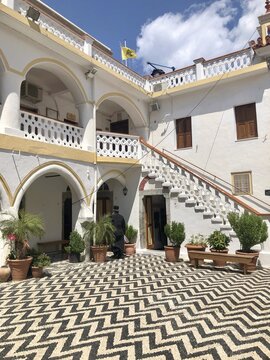 Greek Orthodox clergyman in the courtyard of a monastery, Monastery of Archangel Panormitis, Symi, Dodecanese, Greece