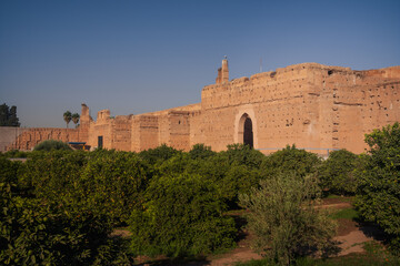 Fototapeta premium Historic walls of El Badi Palace in Marrakech during golden hour light. Iconic Moroccan architecture and ancient fortress surrounded by palm trees and gardens.