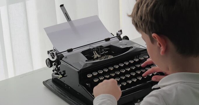 Over-the-shoulder view of a young child carefully pressing the keys on a vintage black manual typewriter
