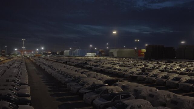 Night view down long rows of parked cars at port vehicle terminal