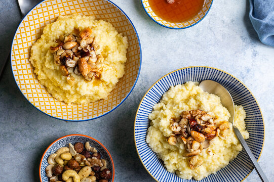 Delicious healthy breakfast: millet porridge cooked with coconut milk and toped up with caramelised mixed nuts and maple syrup