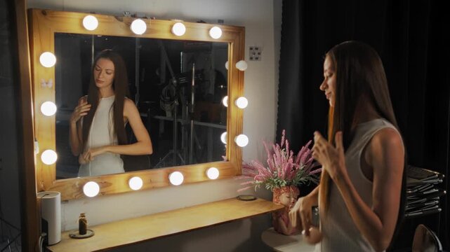 Woman with long brown hair combing her hair in a dressing room