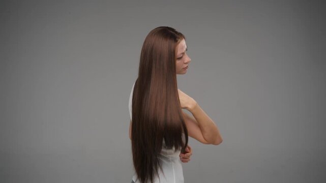Side view of young female model showcasing long smooth brunette hair