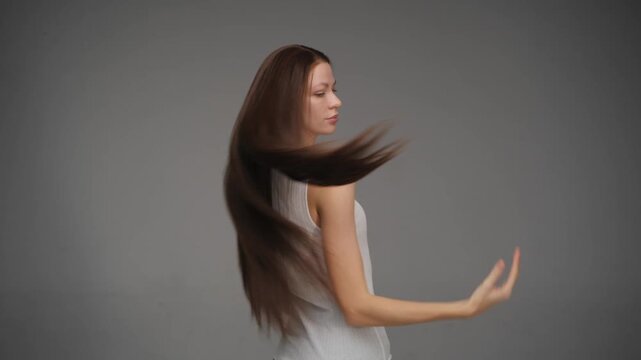 Beautiful brunette woman flipping her long shiny hair in slow motion