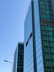 Obraz premium Skyscrapers in the city and blue sky background. Minimalistic architecture made of glass, tall buildings, business and finance, construction industry.